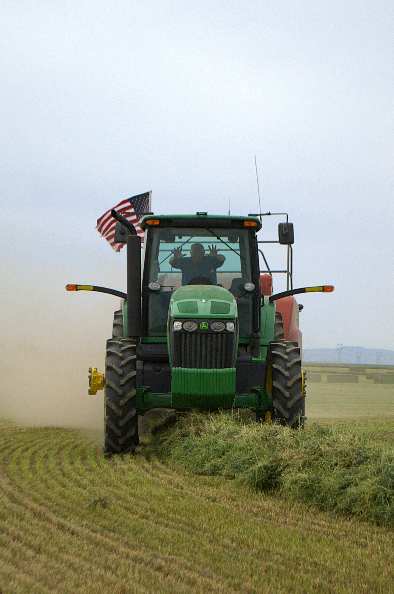 Green tractor in a field with an American flag on the back