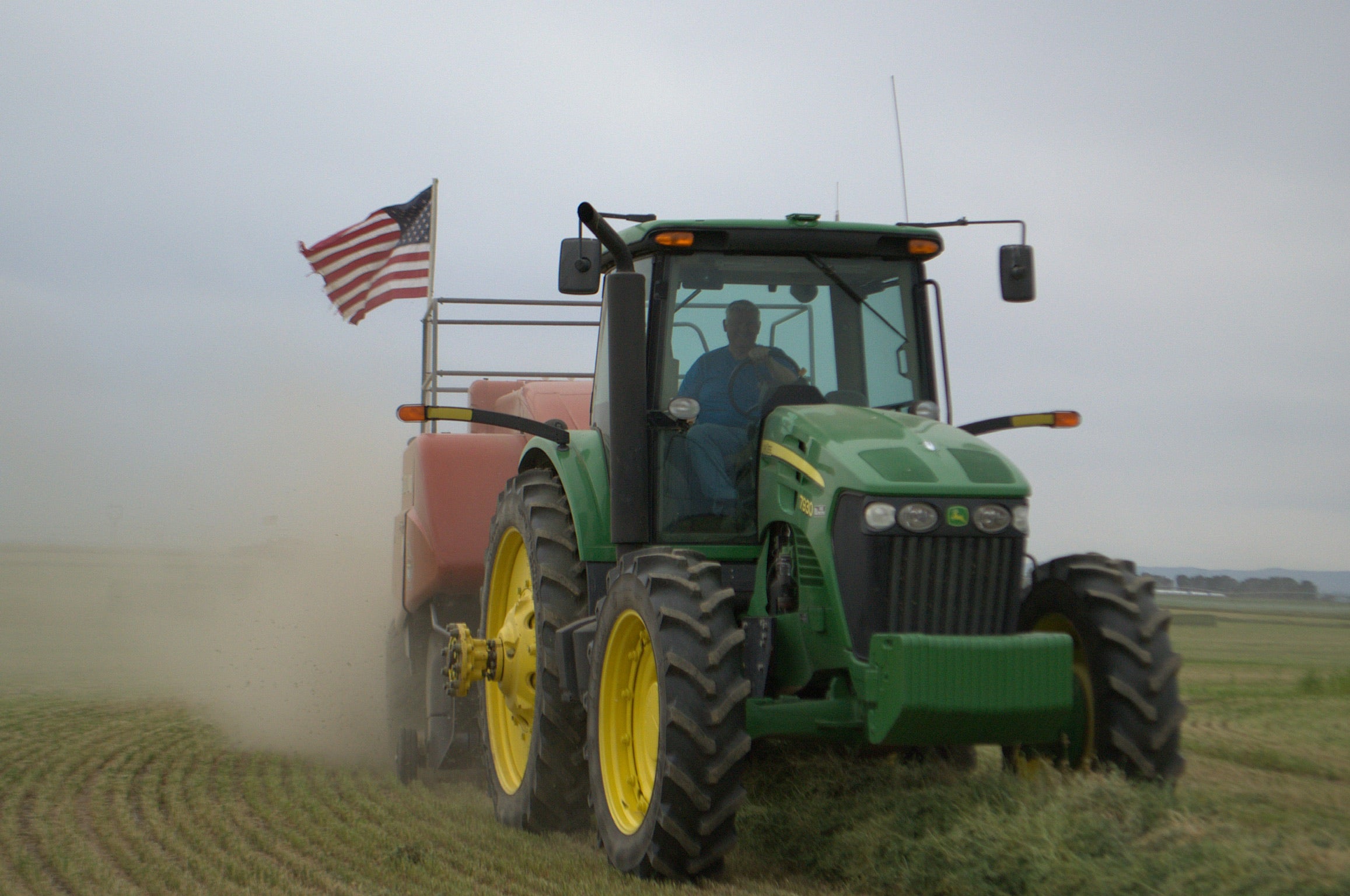 Green tractor with an American flag on a field