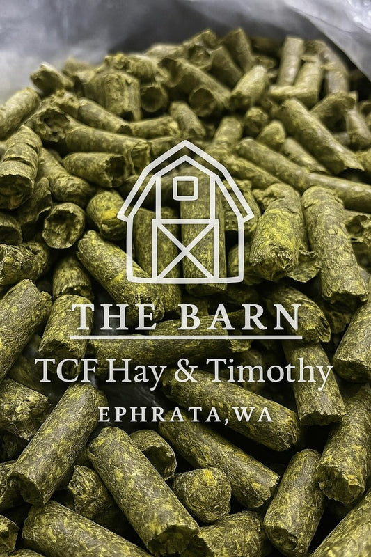 Close-up of green alfalfa pellets with The Barn TCF Hay & Timothy logo and Ephrata, WA text